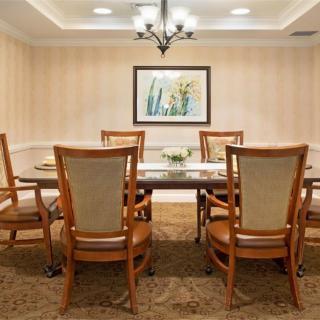 A well-decorated dining room with a large table, six chairs, and a chandelier overhead.