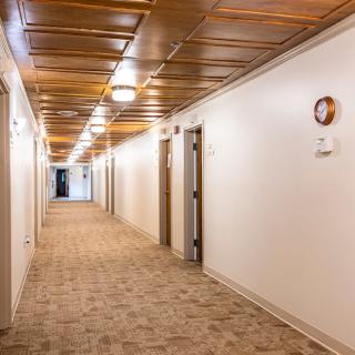 A well-lit corridor with a carpeted floor and multiple doors.