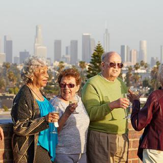 A group of seniors enjoying a social gathering with a city skyline in the background.