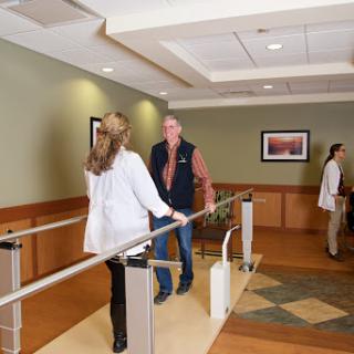 A physical therapy session in a healthcare facility, with a patient practicing walking with the assistance of medical staff.