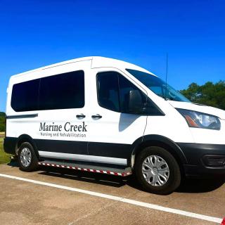 A branded white van parked in a parking lot under a clear blue sky.