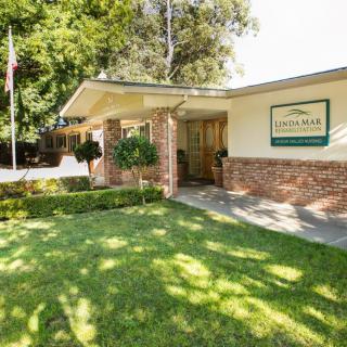 A well-maintained building entrance with a sign and neatly trimmed landscaping.