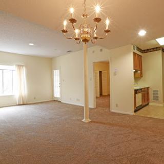 A spacious living room with a chandelier and ample natural light.