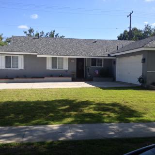 A sunny suburban single-story house with a well-kept lawn and an attached garage.