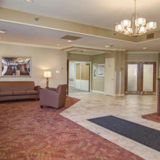 A spacious lobby area with comfortable seating, a chandelier, and carpeted flooring.