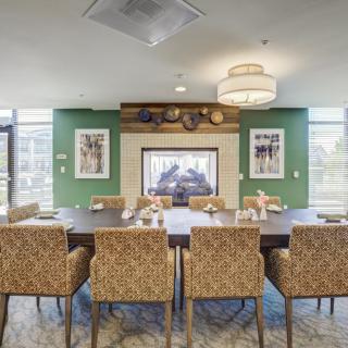A modern dining room featuring a large table with patterned chairs and a fireplace, surrounded by elegant decor.