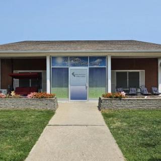 A symmetrical building with a central entrance, surrounded by a well-maintained lawn and pathway.