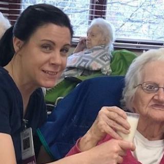 A healthcare worker assists an elderly woman in a nursing home.