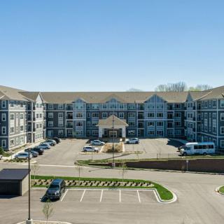A modern residential apartment complex with a large parking lot in front.