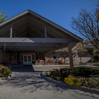 A building entrance surrounded by landscaped greenery and trees.