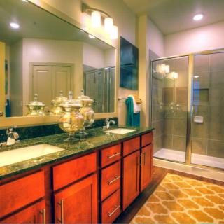 A modern bathroom with a large vanity, spacious shower, and warm lighting.