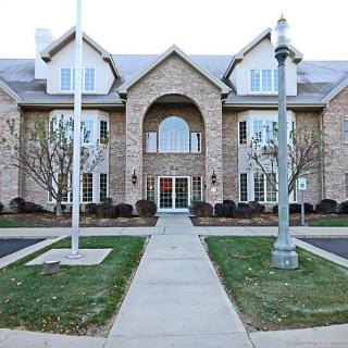 A large, symmetrical brick residential building with a central entrance and a well-maintained lawn.