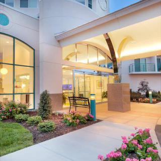 A well-lit hotel entrance with modern architecture and landscaped surroundings during the evening.