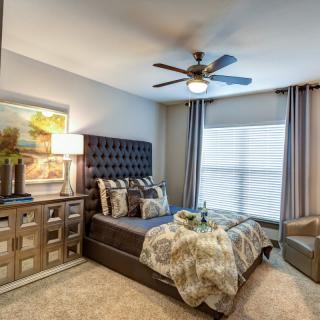 A beautifully decorated bedroom featuring a stylish bed with patterned bedding, a modern lamp, and elegant curtains.