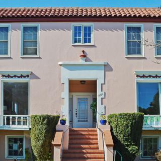 A charming house with a tiled roof and neatly trimmed bushes flanking the entrance stairs.