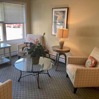 A cozy living room setup with armchairs, a glass coffee table, and a lamp.