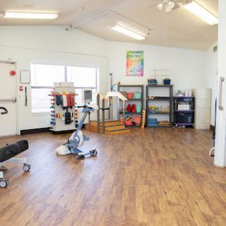 A well-equipped rehabilitation exercise room featuring various fitness tools and a spacious layout.