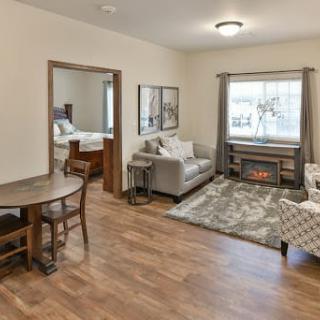 A cozy living room with a dining area and a view into the bedroom, featuring hardwood floors and comfortable seating.