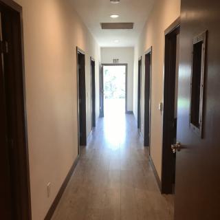 A well-lit corridor with multiple doors and a visible exit at the end.
