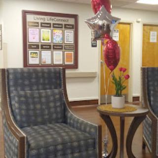 A cozy waiting area featuring comfortable chairs, decorative balloons, and a flower arrangement.