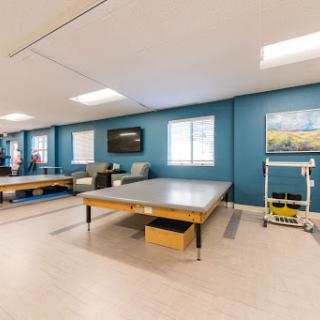 A well-lit therapy room featuring modern tables and calming artwork, designed for rehabilitation purposes.