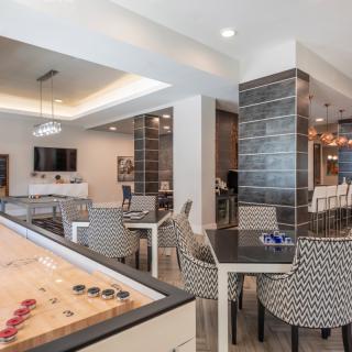 A modern game room featuring a shuffleboard table and comfortable seating.