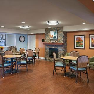 A cozy dining area featuring tables and chairs, a fireplace, and decorative artwork on the walls.