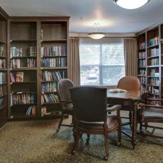 A cozy library reading nook with bookshelves, a table, and chairs.