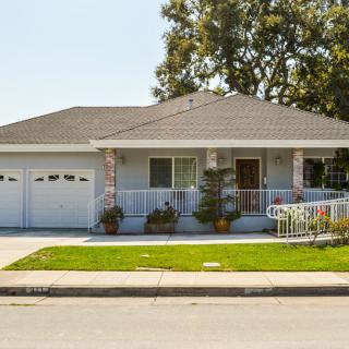 A suburban single-story house with a well-maintained front yard and a spacious porch.