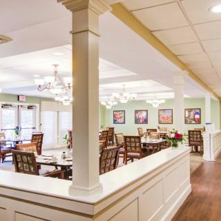A well-lit dining area with elegant chandeliers and neatly arranged tables.