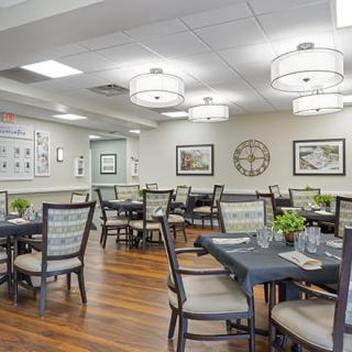 A well-lit dining room with neatly arranged tables and chairs, featuring modern decor and artwork on the walls.