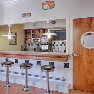 A retro diner interior with a long counter and several bar stools.