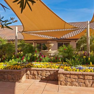 A beautifully landscaped garden with vibrant flowers and shade sails on a sunny day.