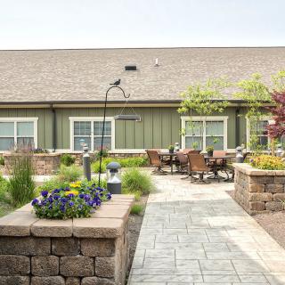 A beautifully landscaped garden with a patio area, featuring outdoor seating and colorful flowers.
