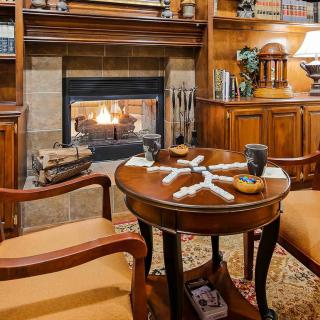 A cozy library setting featuring a fireplace, wooden furniture, and a table with dominoes.