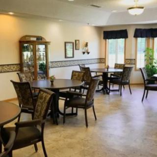 A cozy dining area with multiple tables and chairs, decorated with potted plants and wall art.