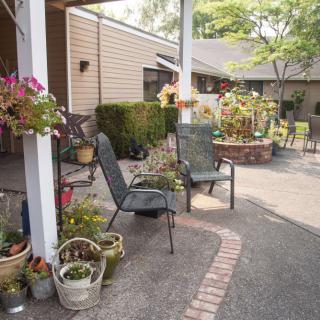 A cozy patio area with chairs and various potted plants, perfect for relaxing in the garden.