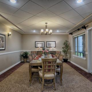 A well-decorated dining room featuring a wooden table, chairs, artwork on the walls, and soft lighting.