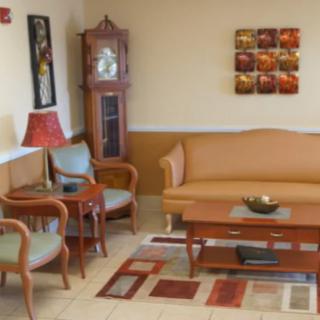 A cozy living room with a couch, chairs, coffee table, and a grandfather clock.
