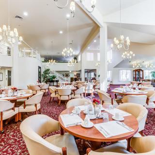 An elegant dining room with chandeliers, set up with tables and chairs.
