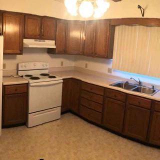 A cozy kitchen featuring wooden cabinets, a stove, and a sink.