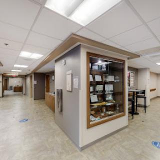 A modern interior view of a hospital corridor, featuring a display case and seating areas.