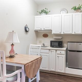 A cozy kitchen and dining area with white cabinets, a small table, and essential appliances.