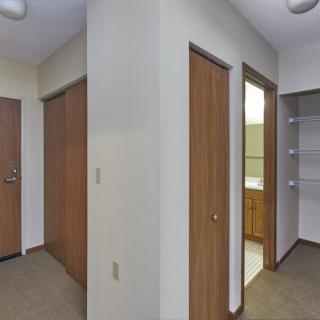 A hallway with multiple wooden doors, including a closet and bathroom entrance.