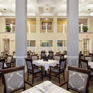 An elegant dining room with multiple tables and chairs, featuring classic decor and soft lighting.