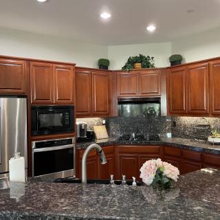 A modern kitchen with wood cabinets, granite countertops, and stainless steel appliances.