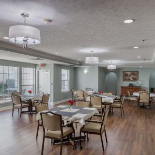 A spacious dining area with neatly arranged tables and chairs, featuring pendant lighting and large windows.