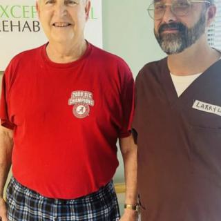 Two individuals standing together in a rehabilitation setting.