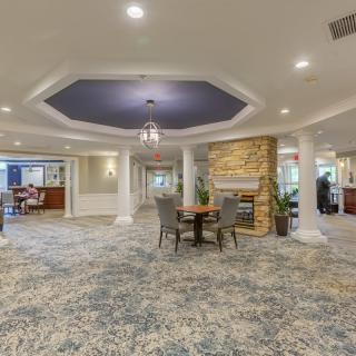 A spacious lobby featuring a cozy seating area with a fireplace, elegant columns, and modern ceiling lights.