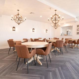 A modern dining area with elegant chandeliers, round tables, and comfortable chairs.